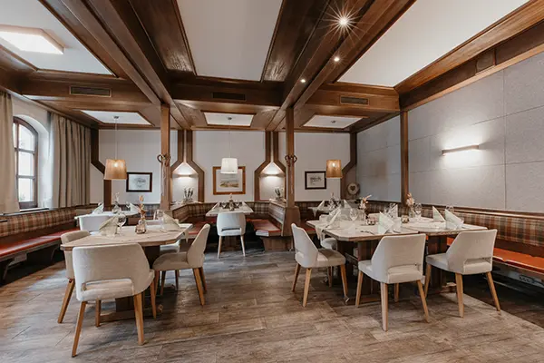 Das Gastzimmer mit gedeckten Tischen und die Theke mit den Barhockern.